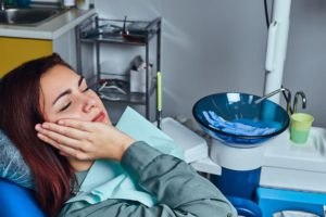 young woman suffering from a toothache while sitti ZEG9SKH 2