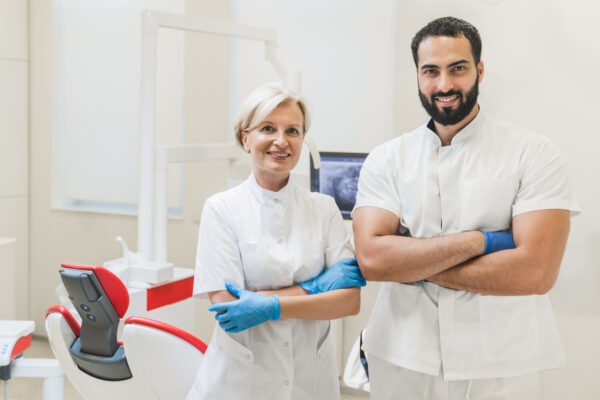 Successful confident two stomatologists orthodontists dentists looking at the camera with arms crossed in dental hospital clinic.