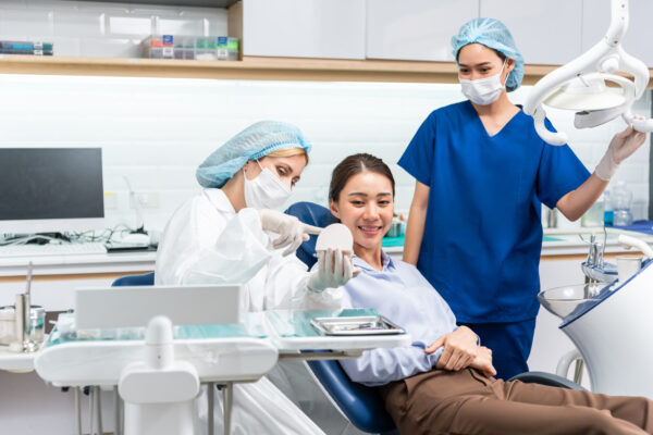 Caucasian dentist examine tooth for young girl at dental health clinic. Attractive woman patient lying on dental chair get dental treatment from doctor during procedure appointment service in hospital